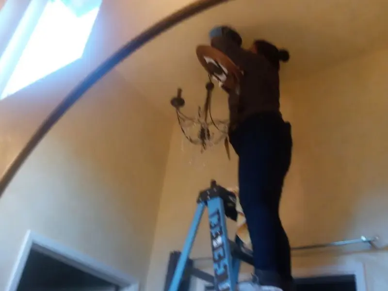 Electrician installing a chandelier in a South Venice residence
